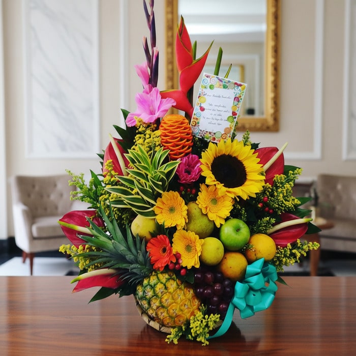 Arreglo floral exótico Antídoto con girasoles, heliconias, gladiolos, piña, uvas, peras y manzanas sobre mesa de madera pulid