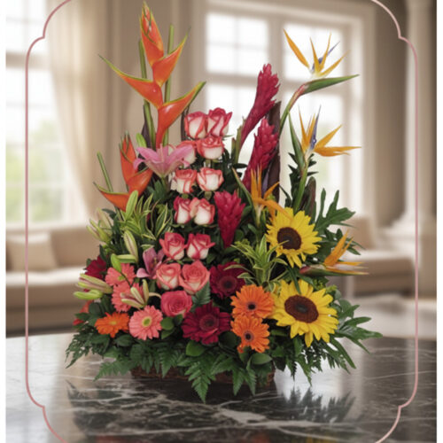 Arreglo floral PIA con rosas rosadas, girasoles, aves del paraíso y flores exóticas en un fondo elegante y luminoso.