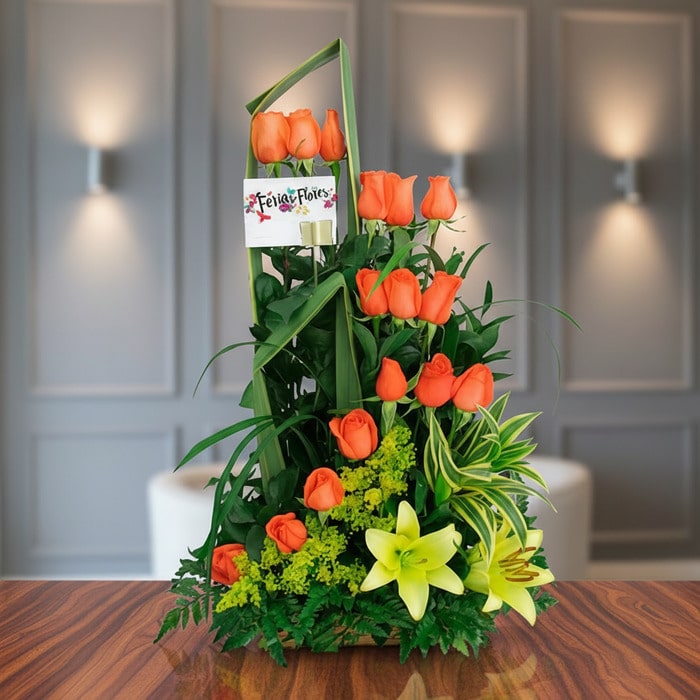 Arreglo floral Romeo con rosas naranjas vibrantes y lirios amarillos, sobre una superficie de madera pulida en un entorno ele